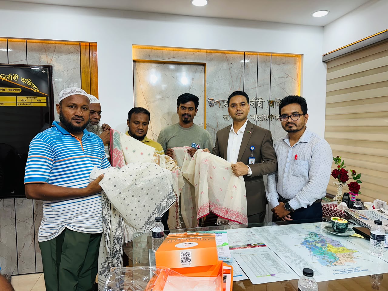 রাষ্ট্রীয় অতিথিবৃন্দকে উপহার দেয়ার জন্য বিসিক জামদানি শিল্পনগরীর দক্ষ কারিগর কর্তৃক তৈরিকৃত জামদানি উত্তরীয় উপজেলা নির্বাহী কর্মকর্তা, রূপগঞ্জ, নারায়ণগঞ্জের হাতে তুলে দেয়া হচ্ছে