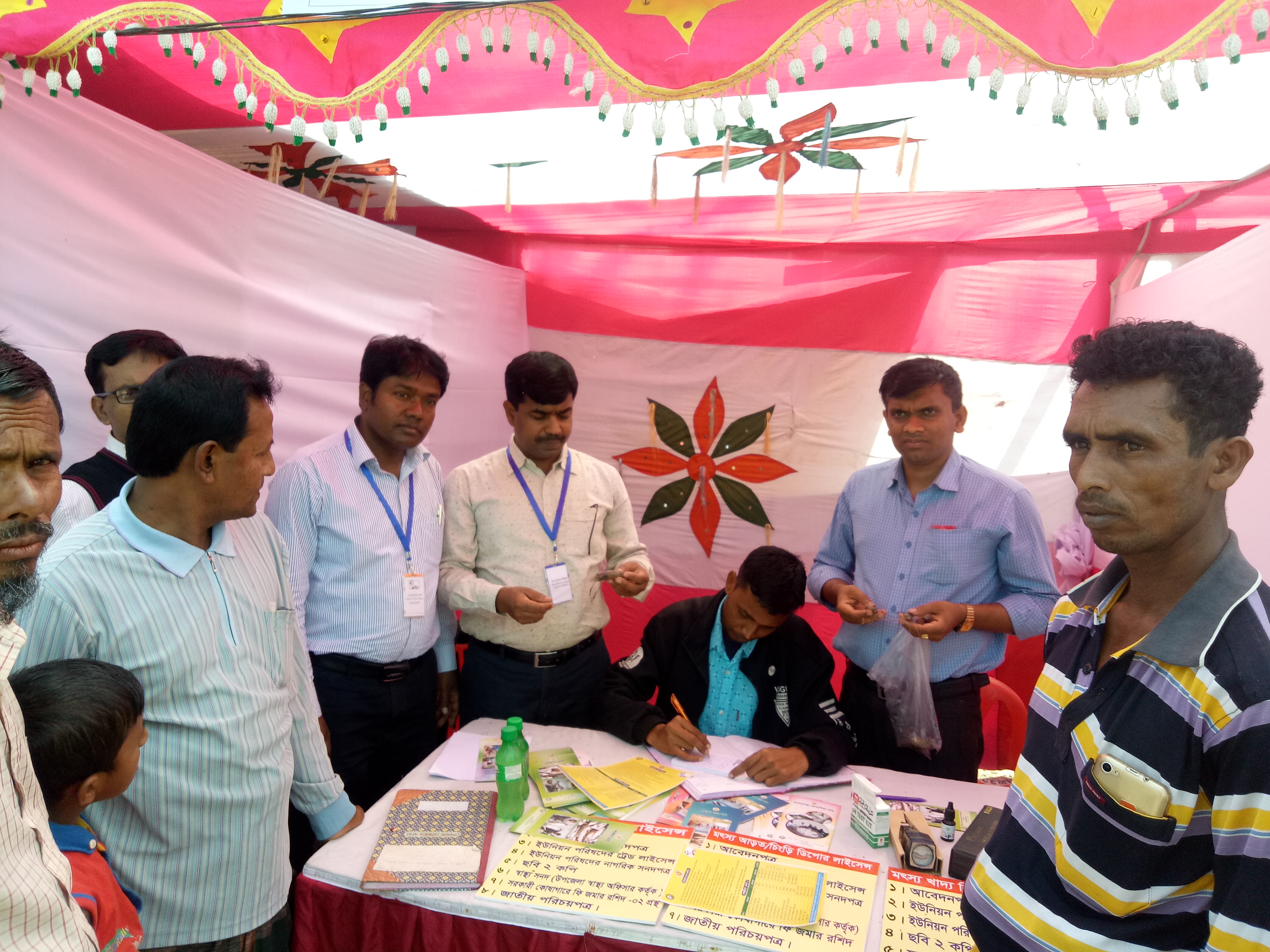 সিনিয়র উপজেলা মৎস্য অফিসার আগত চাষীকে সেবা দিচ্ছেন।