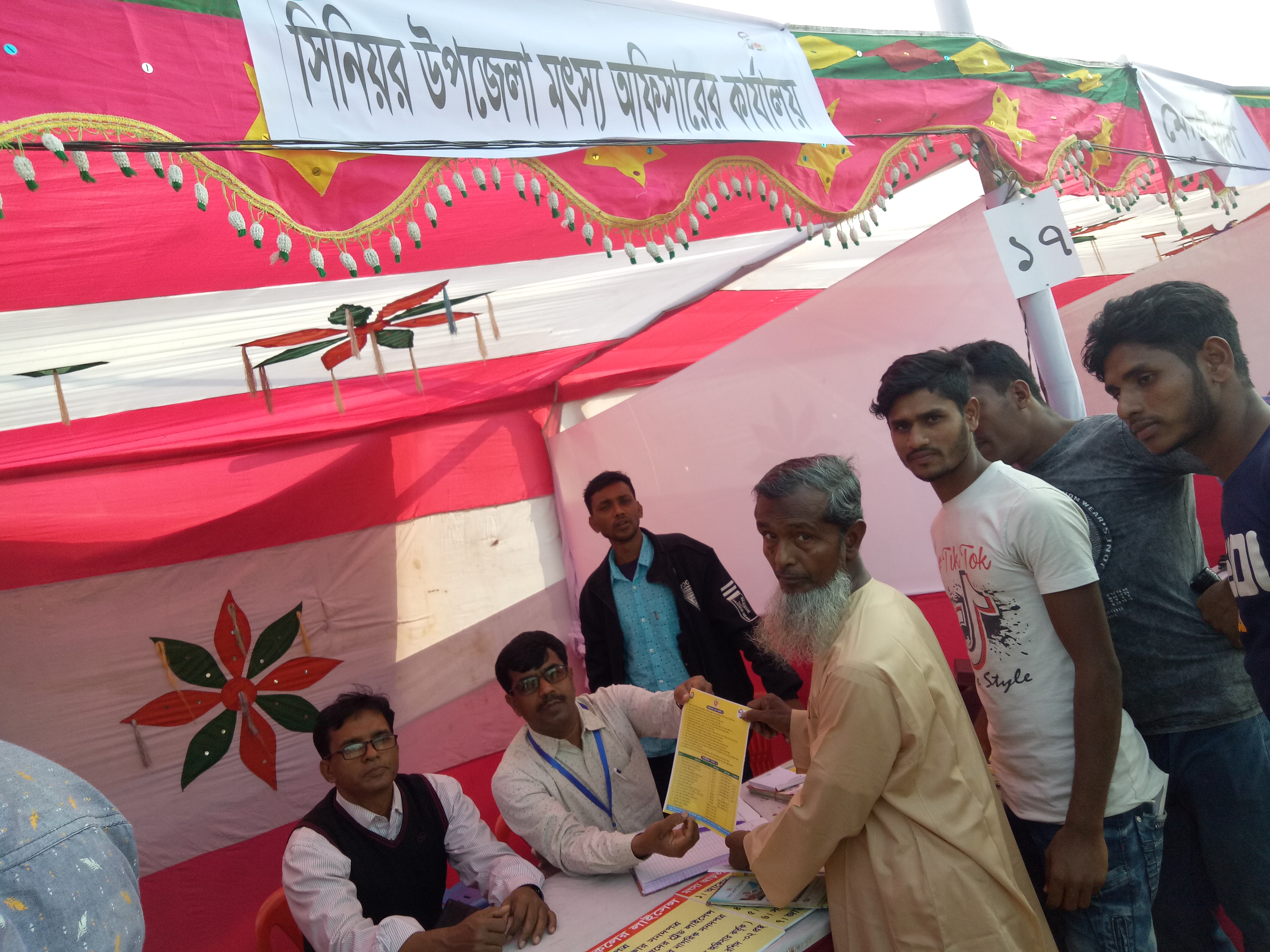 সিনিয়র উপজেলা মৎস্য অফিসার আগত চাষীকে লিফলেট প্রদান করছেন।