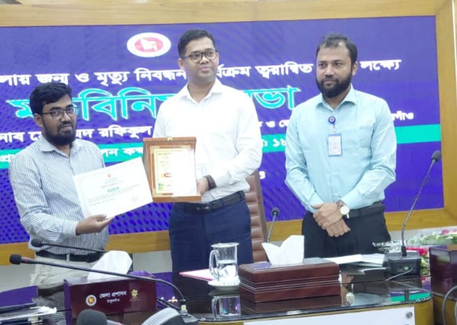জন্ম-মৃত্যু নিবন্ধন জুন ২০২৬ এ জেলা পর্যায়ে ১ম স্থান অর্জন করায় প্রশাসনিক কর্মকর্তা জনাব মোঃ দবিরুল ইসলাম জেলা প্রশাসক মহোদয়ের কাছ থেকে সম্মাননা স্মারক গ্রহণ